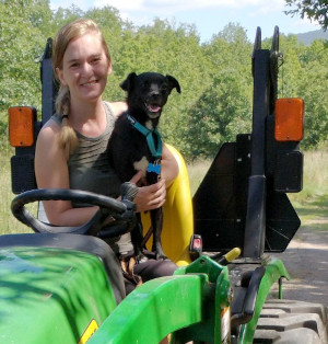 Woman on tractor with adorable little dog on lap